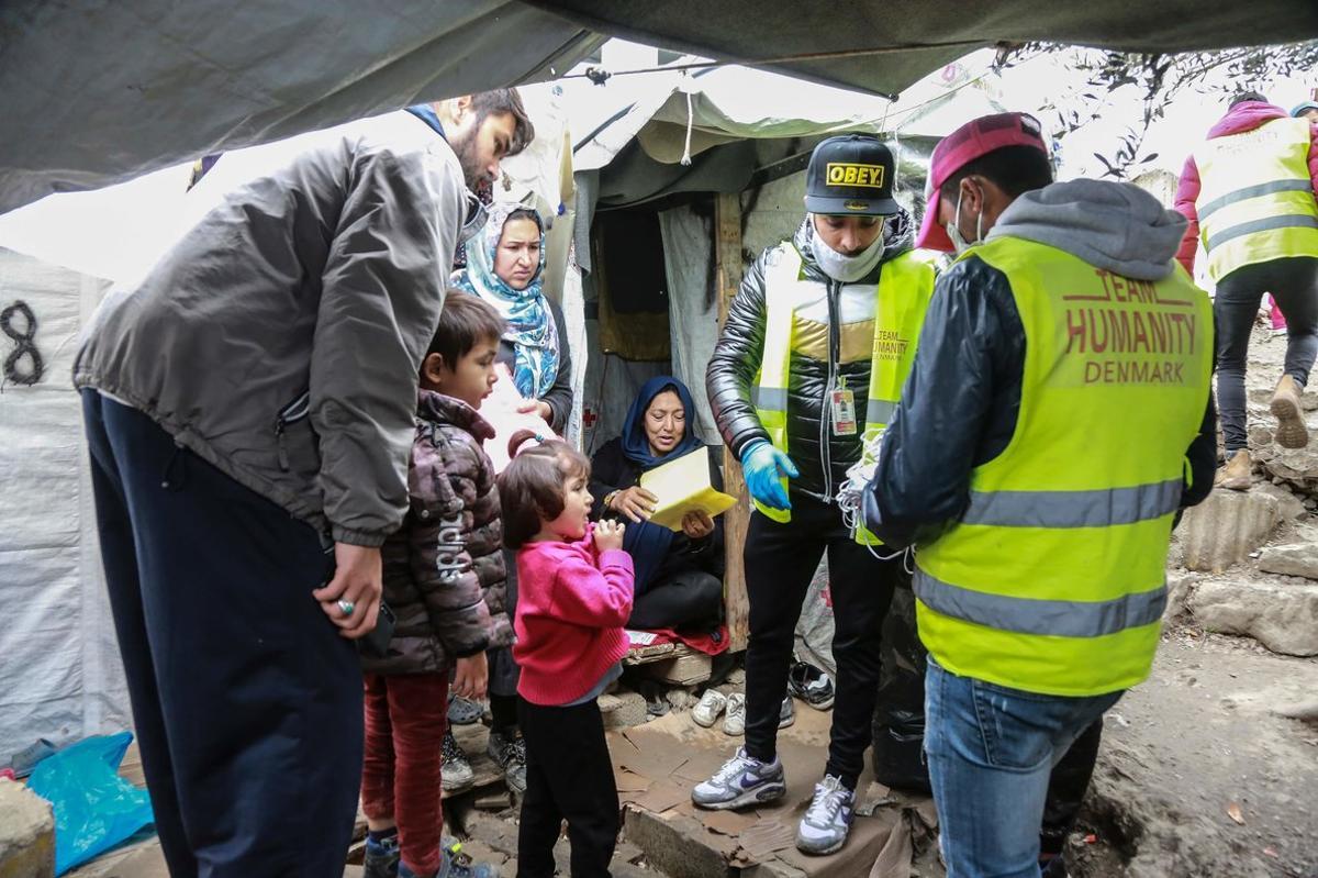 Miembros de la oenegé Team Humanity entregan mascarillas en un campo de refugiados de Lesbos.