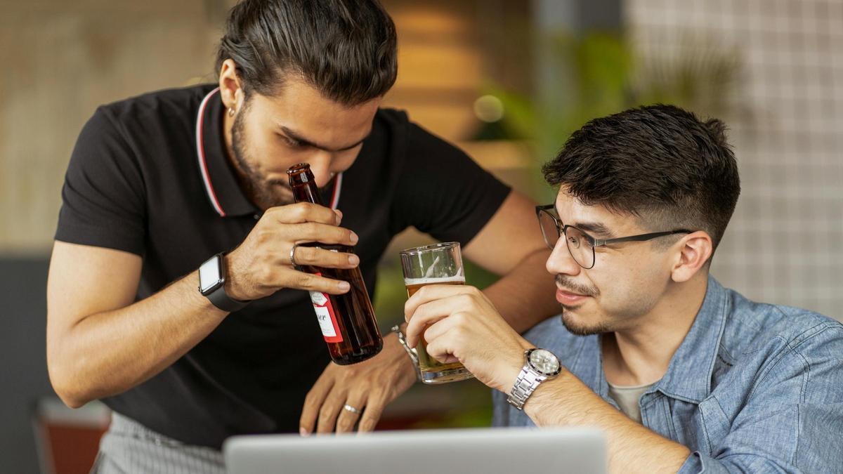 Dos personas brindan con una cerveza en una cena navideña