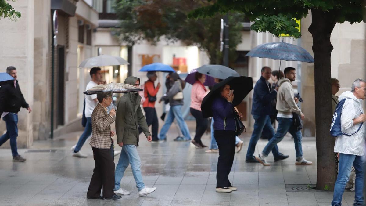 Varias personas se protegen de la lluvia en Zaragoza durante este pasado fin de semana