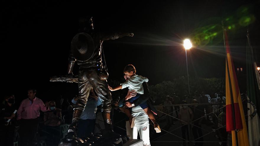 Un adulto acerca a un niño a la escultura del segador recién descubierta.