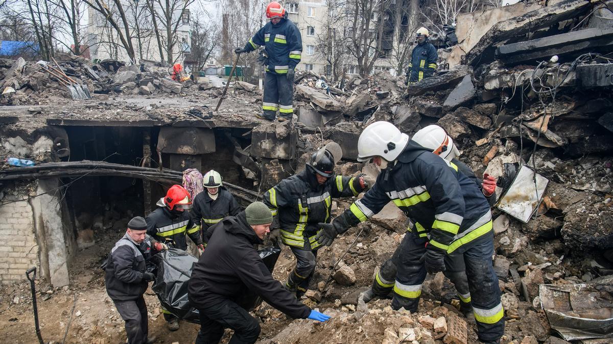Los bomberos llevan el cuerpo de una persona encontrada bajo los escombros de un edificio residencial destruido durante la invasión rusa en la ciudad de Borodianka.