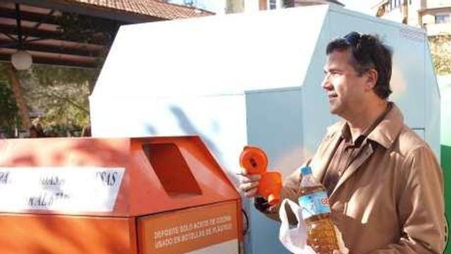El edil Cerdá depositando aceite usado en un contenedor.