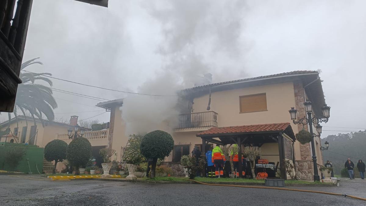 Los servicios de emergencia atienden al matrimonio mientras de su casa sigue saliendo humo del incendio.
