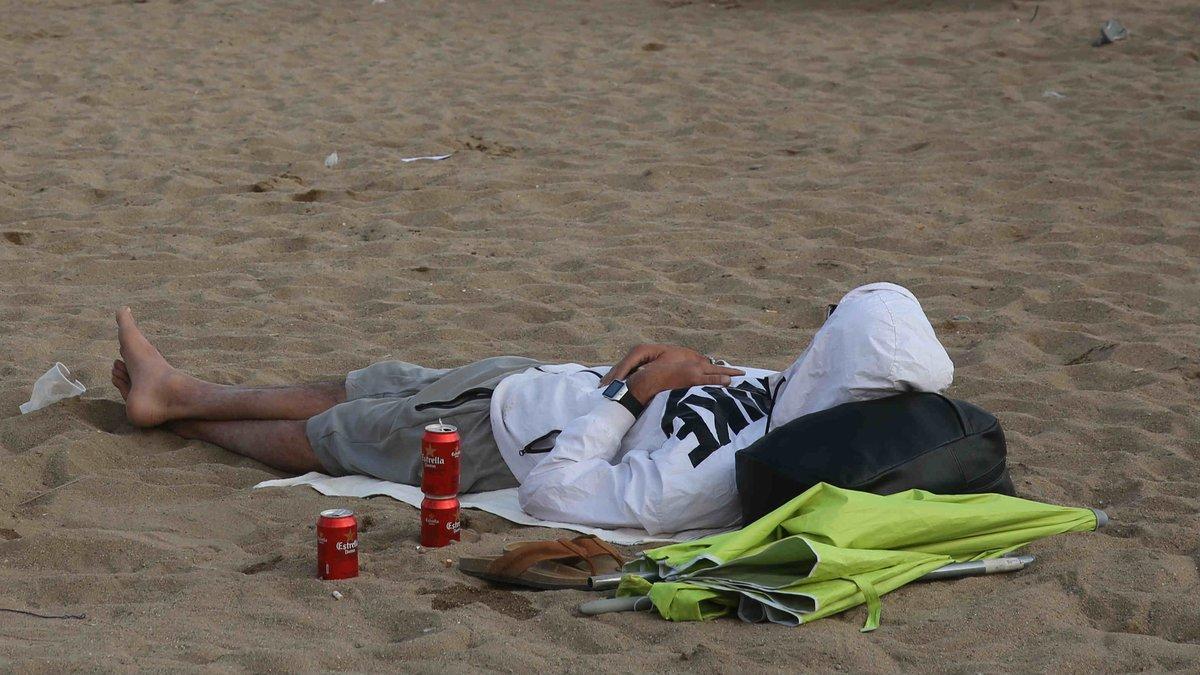 Un hombre durmiendo en la playa de la Barceloneta