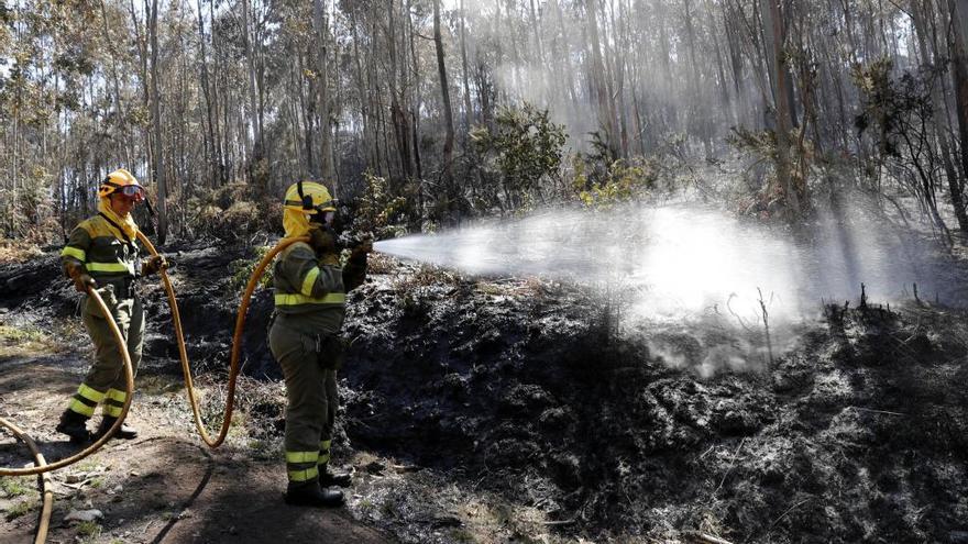 Bomberos refrescando una zona quemada. // J. Lores