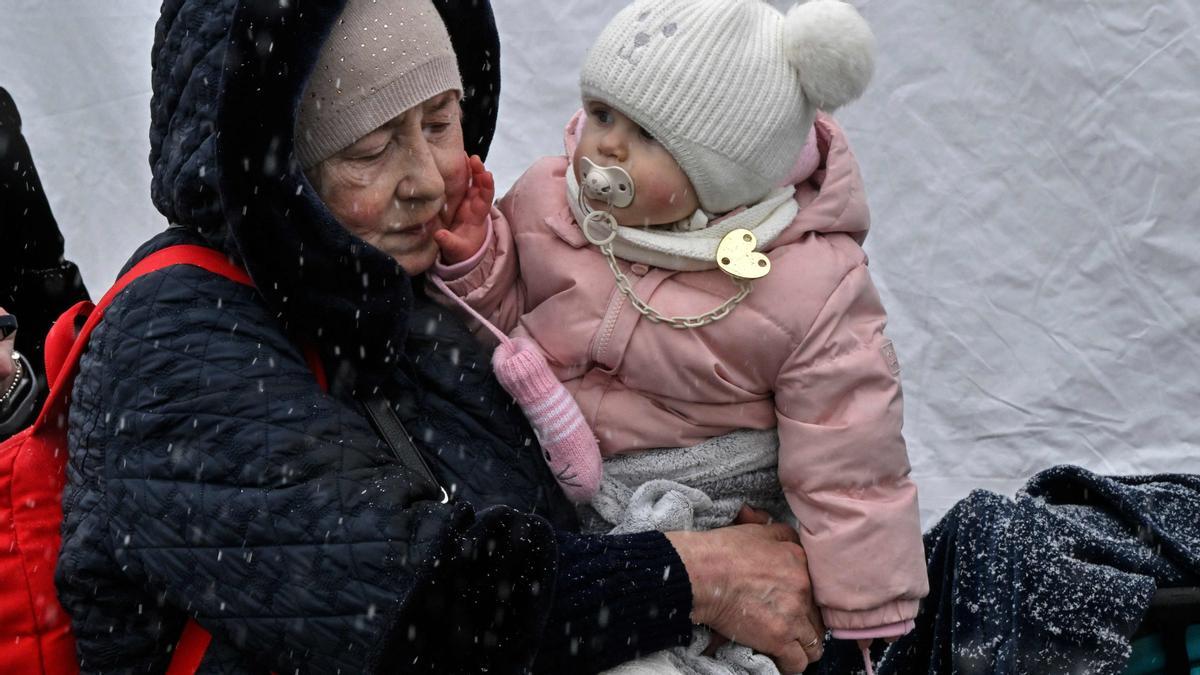 Una mujer sostiene a su nieta durante una nevada en el cruce fronterizo polaco-ucraniano en Medyka, al este de Polonia, el 9 de marzo de 2022.