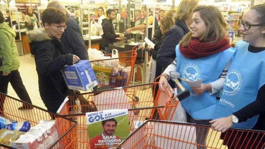 Una mujer entrega una caja de leche a dos voluntarias del Banco de Alimentos.