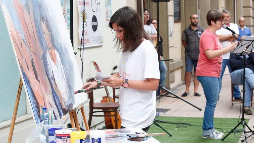 La artista Itziar Sánchez pinta un cuadro inspirado en Picasso mientras la historiadora Patricia Pérez contextualiza al público sobre la vida y obra del pintor, ayer, en la calle Palacio Valdés.