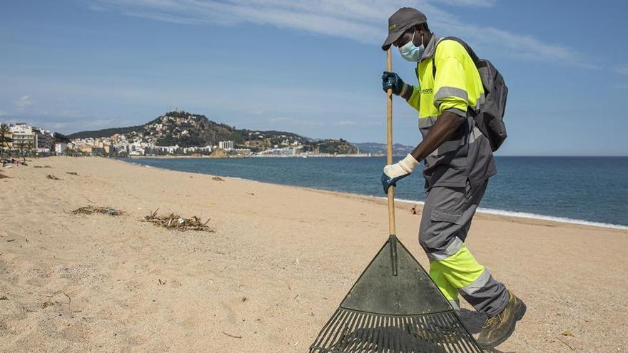 Un operari treballant en una platja de Blanes deserta