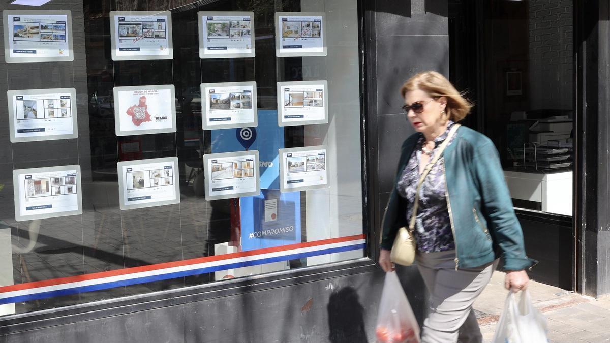 Una mujer pasa por delante del escaparate de una inmobiliaria en el centro de la ciudad de Murcia.