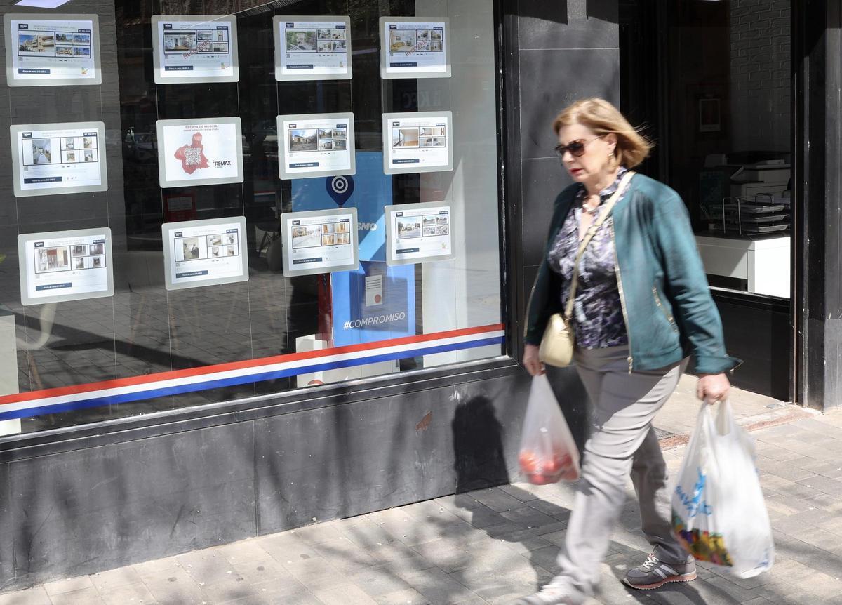 Una mujer pasa por delante del escaparate de una inmobiliaria en el centro de la ciudad de Murcia.