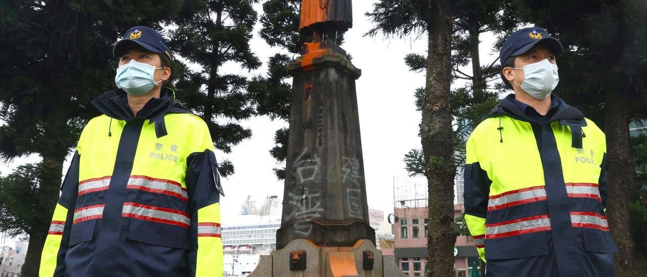 Police officers guard a vandalised statue of late Taiwanese President Chiang Kai-shek in Keelung