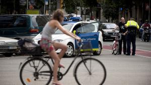 Una ciclista observa cómo un guardia urbano multa a una persona que va en bicicleta por saltarse un semáforo (Imagen de archivo).