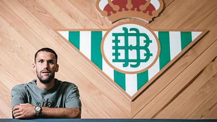 El jugador posando junto a un escudo del Betis