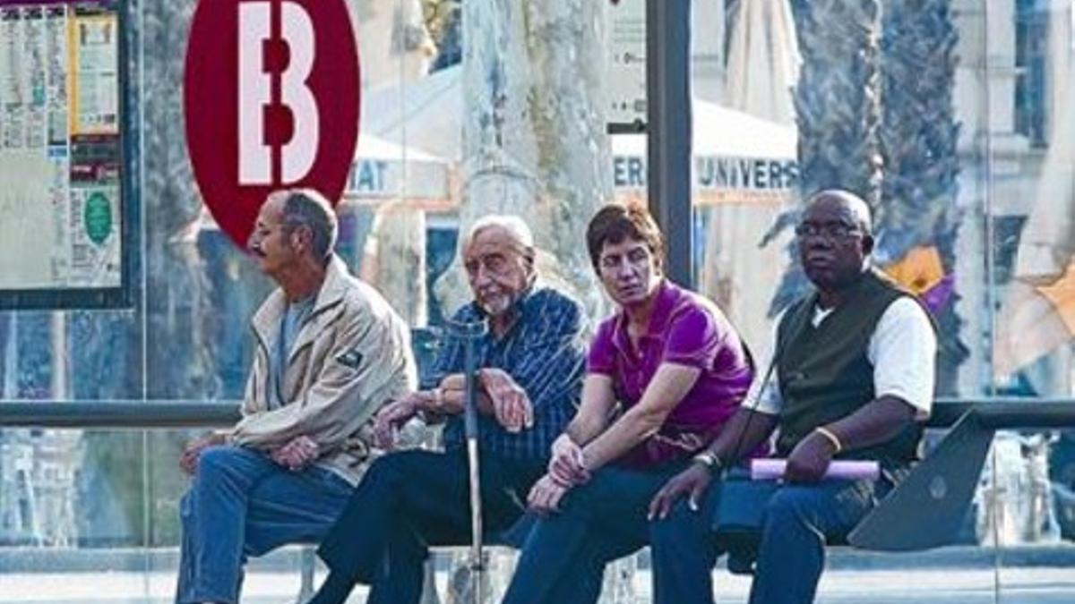 Cuatro usuarios esperan el bus en una parada de la Gran Via durante la huelga del lunes.