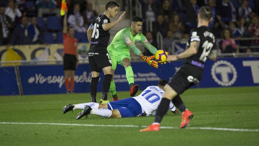 Munir, portero del Málaga CF, atrapa el balón ante la mirada de Ricca y el chicharrero Suso, tendido en el suelo.