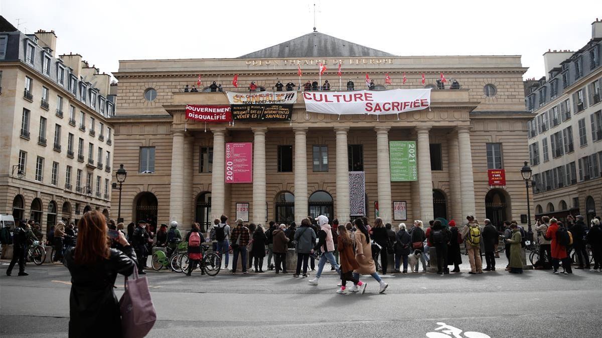 Culture workers and artists hang banners and flags from the balcony of the Theatre de l Odeon  to protest against the French government decision to keep theatres  cinemas  concert halls and museums closed until further notice to combat a resurgence of the coronavirus disease (COVID-19) outbreak in Paris  France  March 12  2021  REUTERS Benoit Tessier