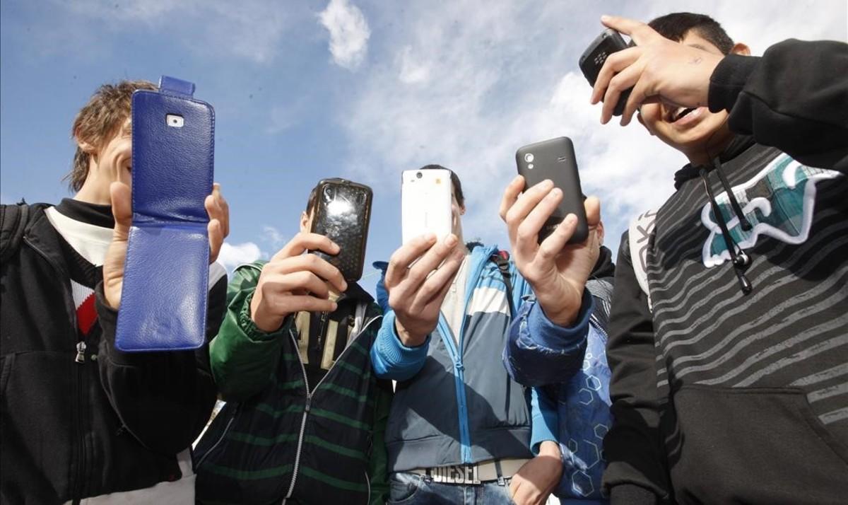 Adolescentes consultan redes sociales en el móvil.