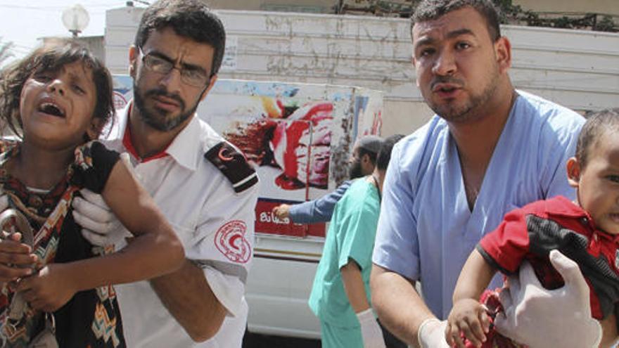 Dos palestinos trasladan a niños heridos en Gaza en 2014.