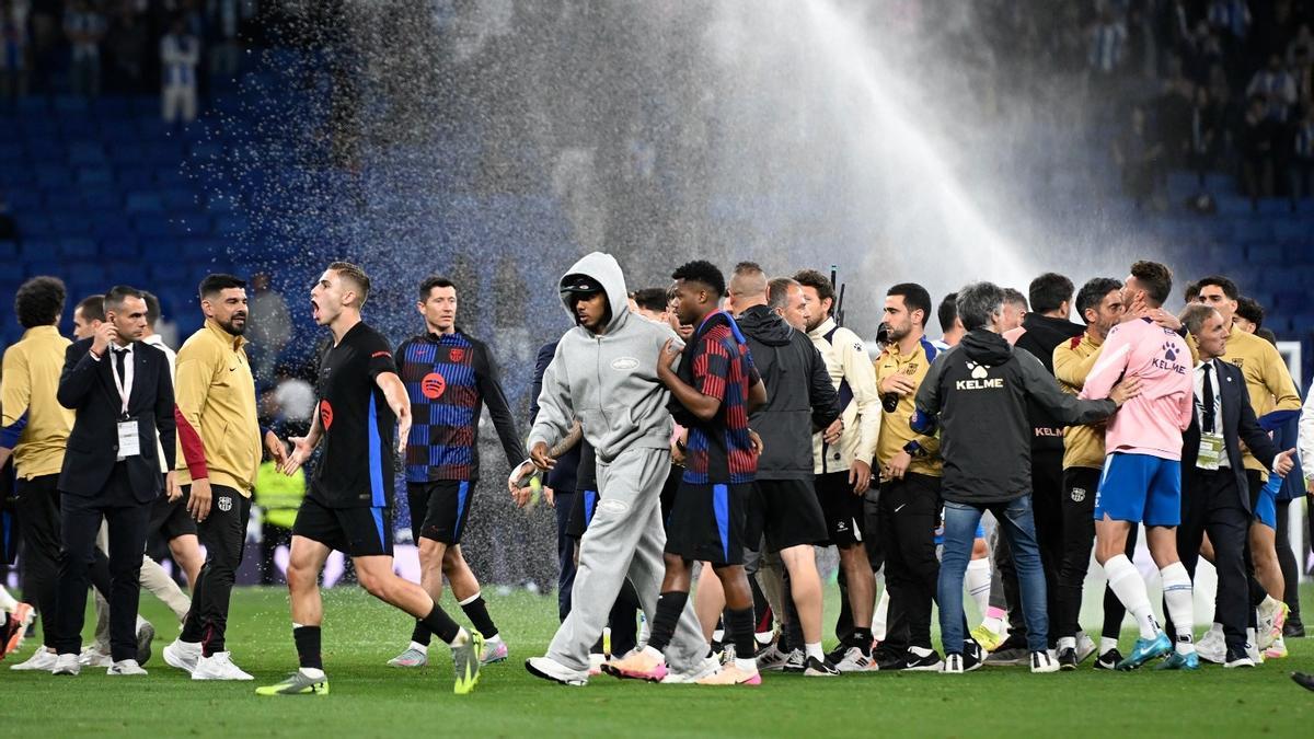 Los jugadores del Barça, bajo el agua de los aspersores.