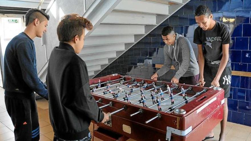 Quatre adolescents del centre, fent temps un matí jugant al futbolí, abans no comencin les classes