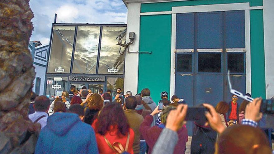 Un grupo de personas observan el último eclipse de Sol en Canarias, reflejado en la cristalera del Edificio Elder.