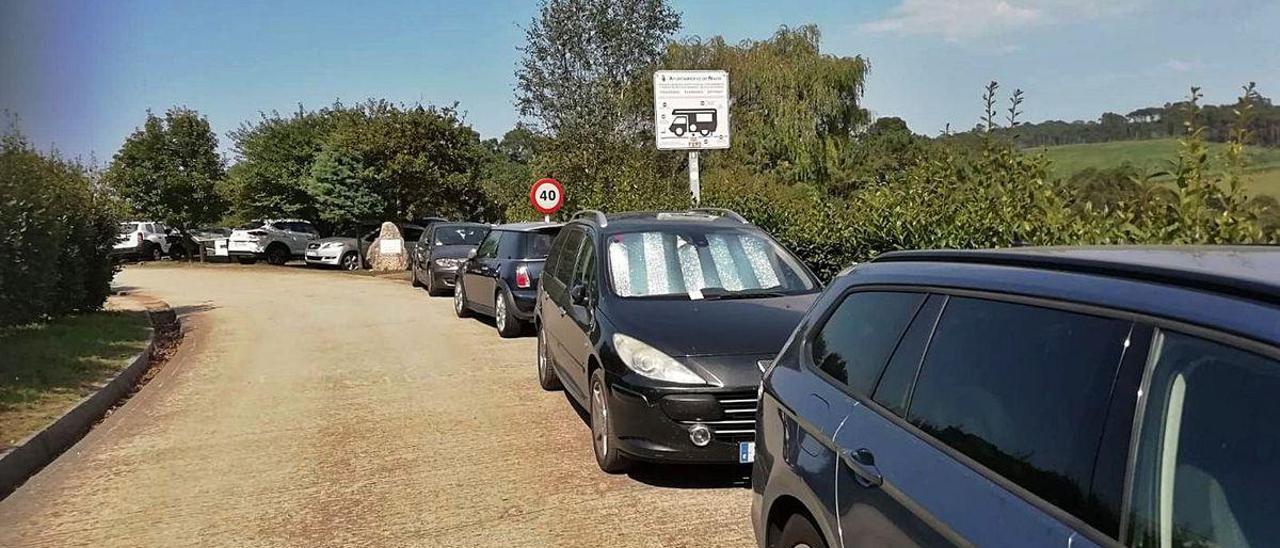 Turismos estacionados en la vía de acceso al arenal de Frejulfe.