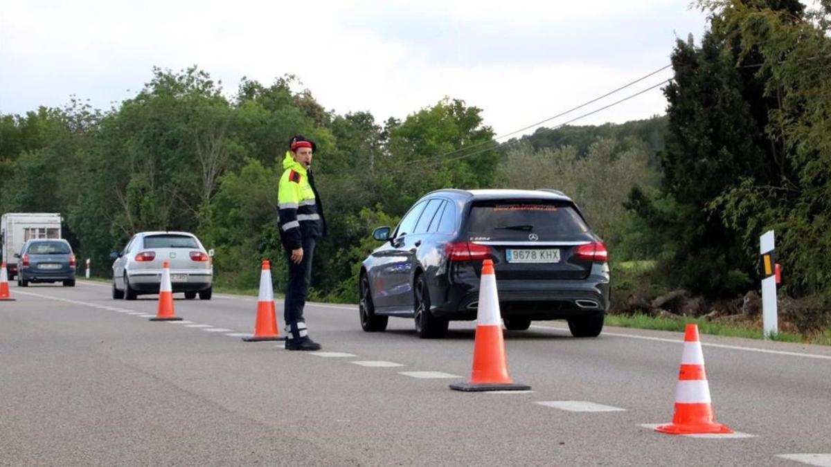 Un mosso regula el tráfico en la N-II a su paso por Bàscara, tras el accidente de una furgoneta.