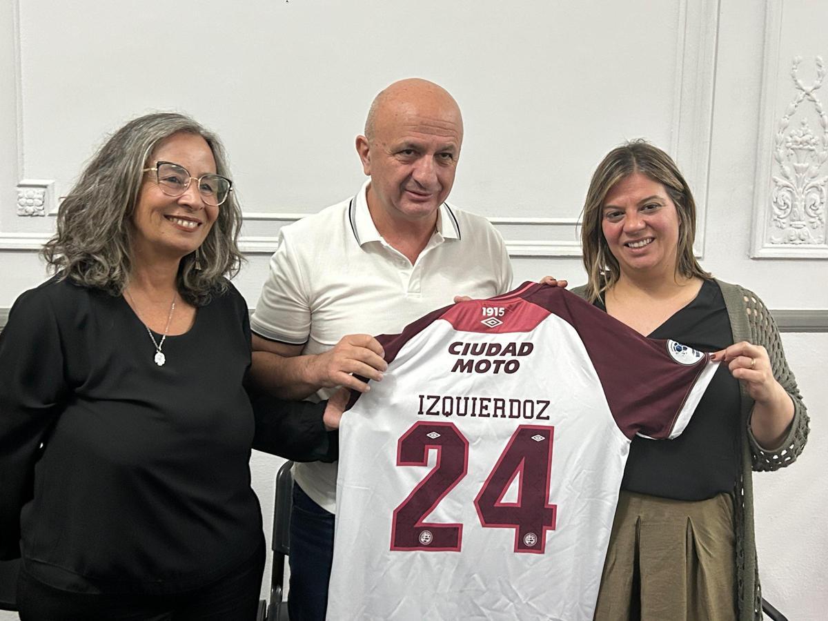 Nicolás Russo entrega a Gimena Llamedo la camiseta de Izquierdoz junto a la secretaria de Educación y Cultura del Consejo Deliberante de Lanús.