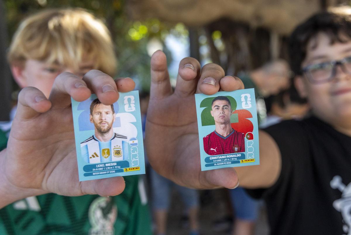 Dos niños enseñan los cromos de Messi y Cristiano, este viernes en Canalejas.