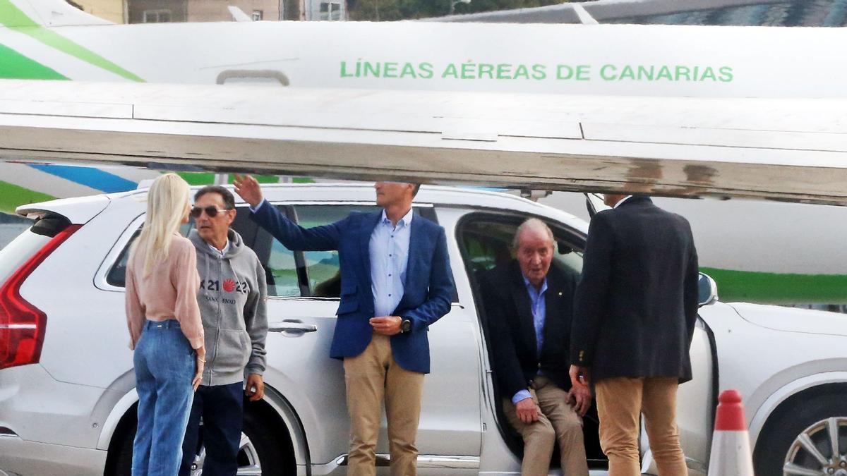 El rey emérito se introduce en un coche con el avión de Binter de fondo.