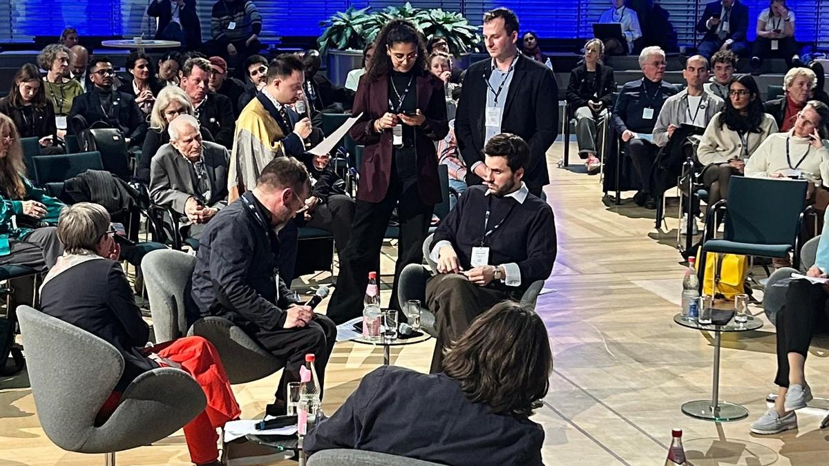 Un momento de la intervención de Eros Recio, ataviado con la bandera de la Superación, en la conferencia de Berlín.