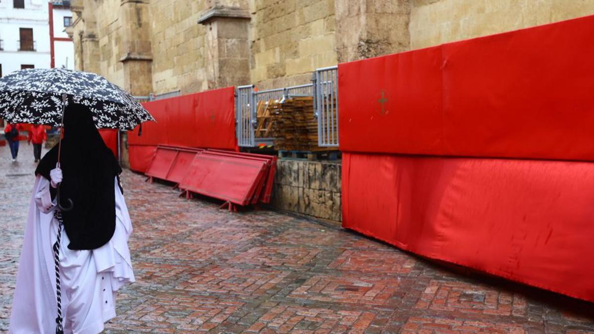 Un nazareno con paraguas cruza la carrera oficial 2024.