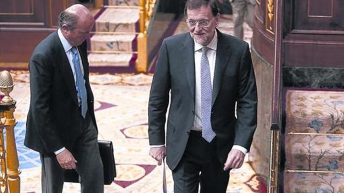 El presidente del Gobierno, Mariano Rajoy, seguido por el ministro de Economía, Luis de Guindos, en una sesión de control al Gobierno.
