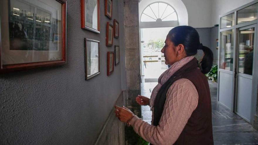 María José García coloca unas fotografías enmarcadas en el pasillo de entrada del instituto.