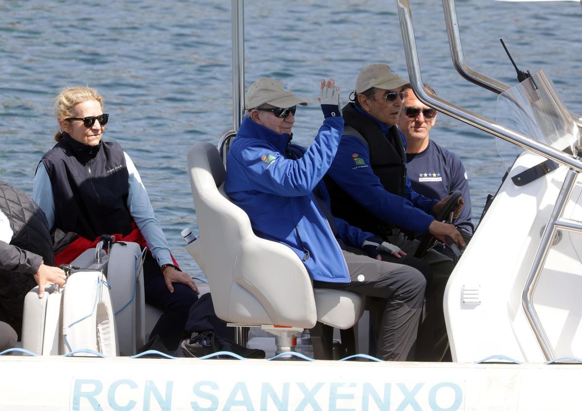 El rey emérito saluda desde el barco con su hija Elena sentada tras él.