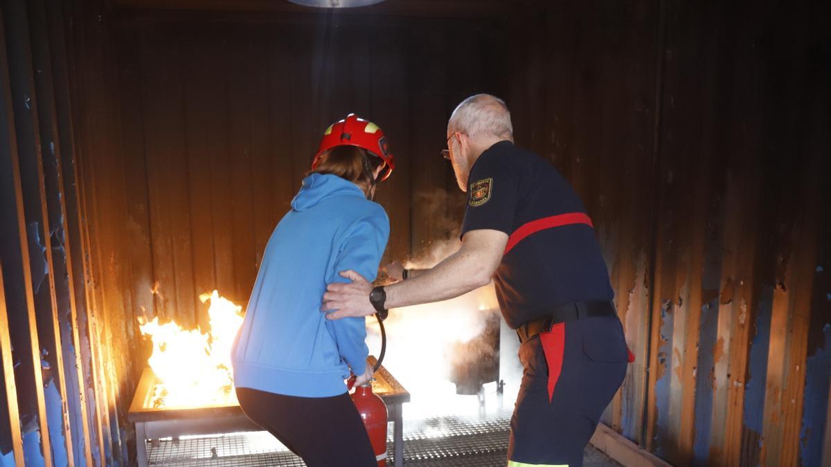 Un bombero enseña a utilizar un extintor a la profesora de un colegio.