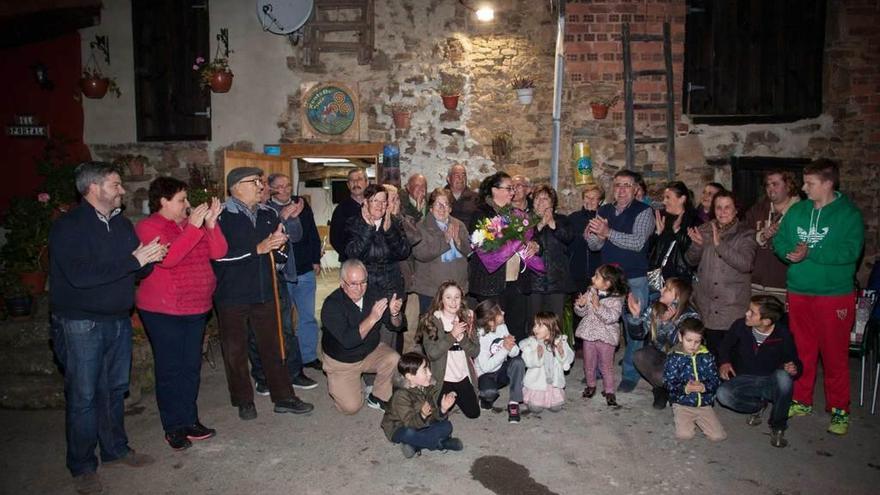 Los vecinos, ante la sede de la asociación cultural, con Patricia Otero con un ramo de flores.