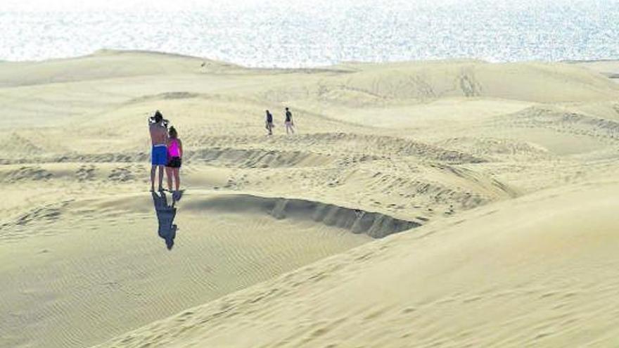 Una pareja de turistas fotografía las dunas de Maspalomas, en Gran Canaria. | | JUAN CARLOS CASTRO