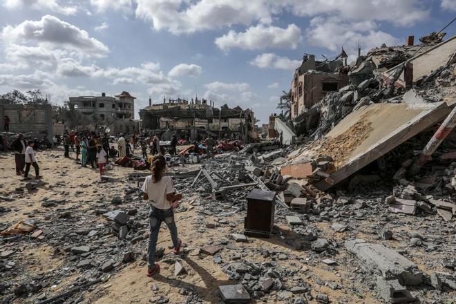 Varias personas observan edificios destruidos por bombardeos de Israel.