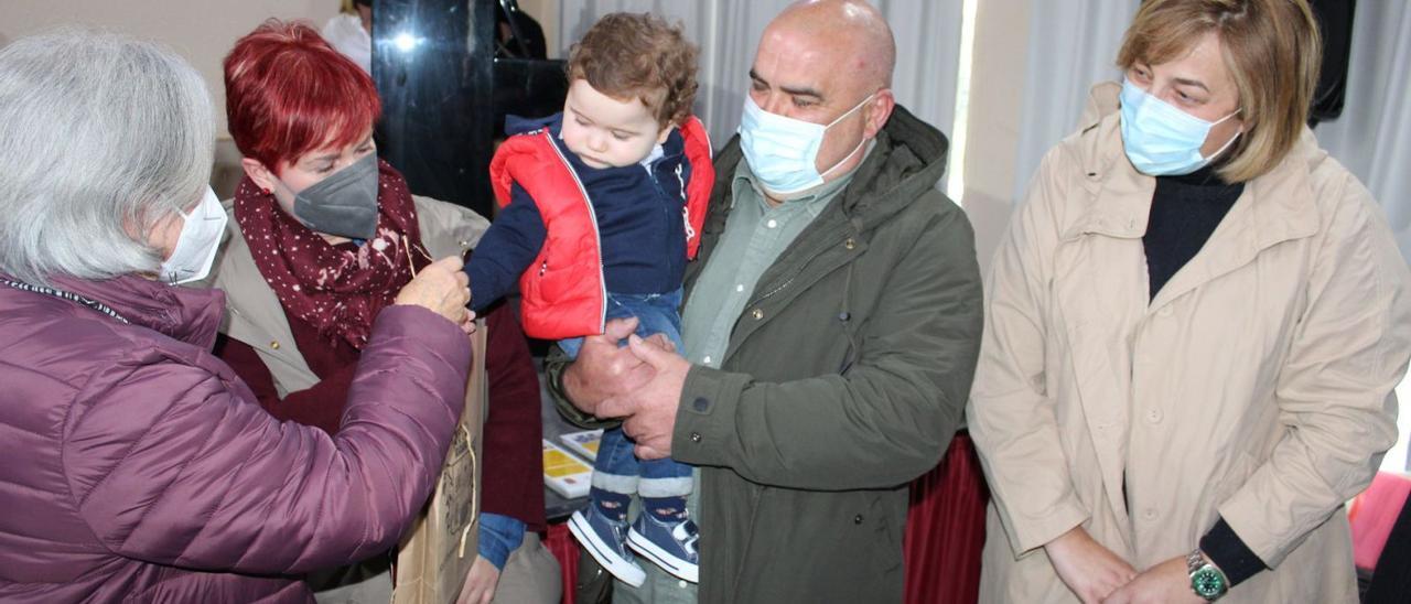 El pequeño Álex Arruñada, junto a sus padres, Henar García y Alberto Arruñada, recibe su carné lector de manos de la concejala de Cultura de Coaña,  Guadalupe Junco, en presencia de la alcaldesa de Coaña, Rosana González. | T. Cascudo