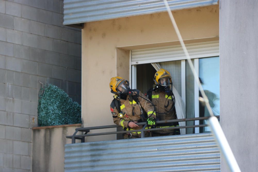 Dos Bombers treballant en el balcó d'una de les habitacions de l'habitatge afectat
