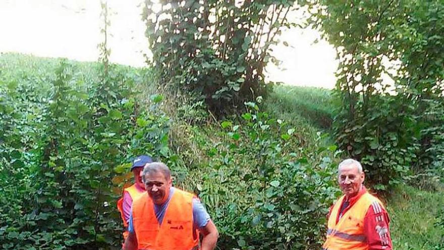 Tres pescadores caminan por el río portando bolsas de basura.