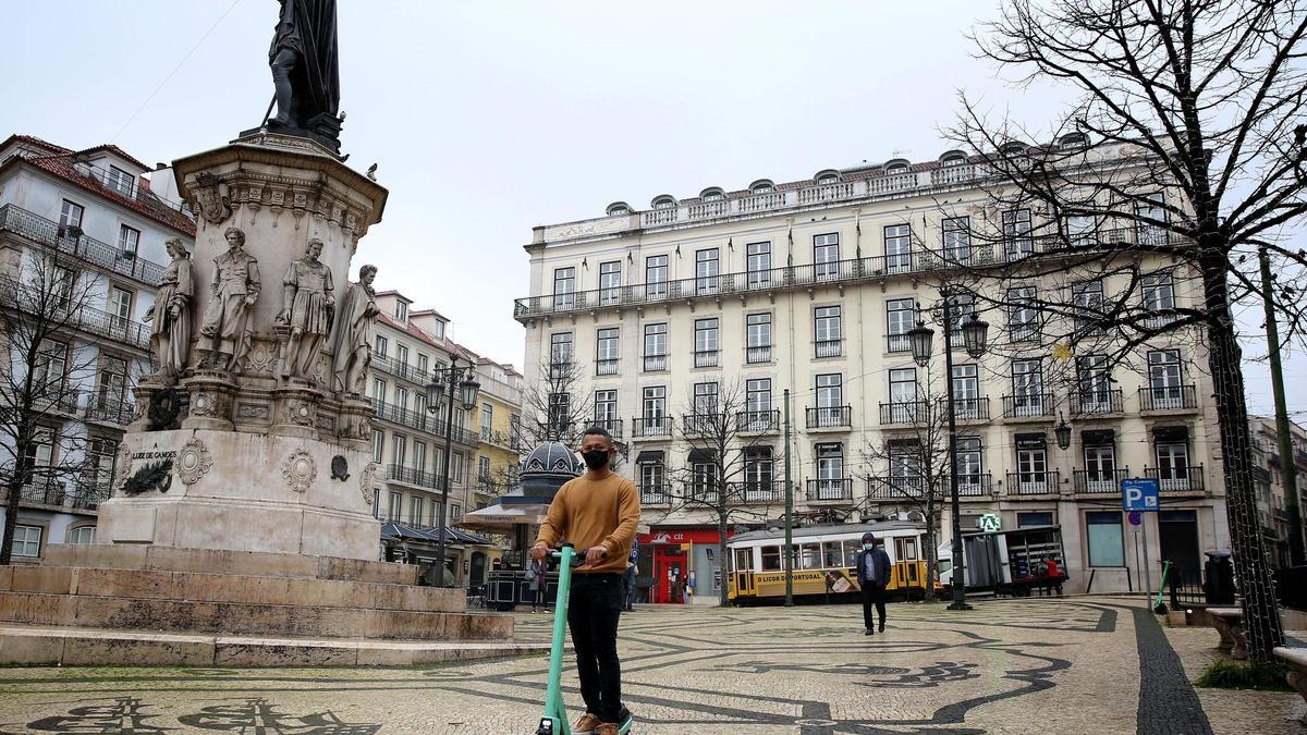 Un joven con mascarilla pasea en un patinete por Lisboa