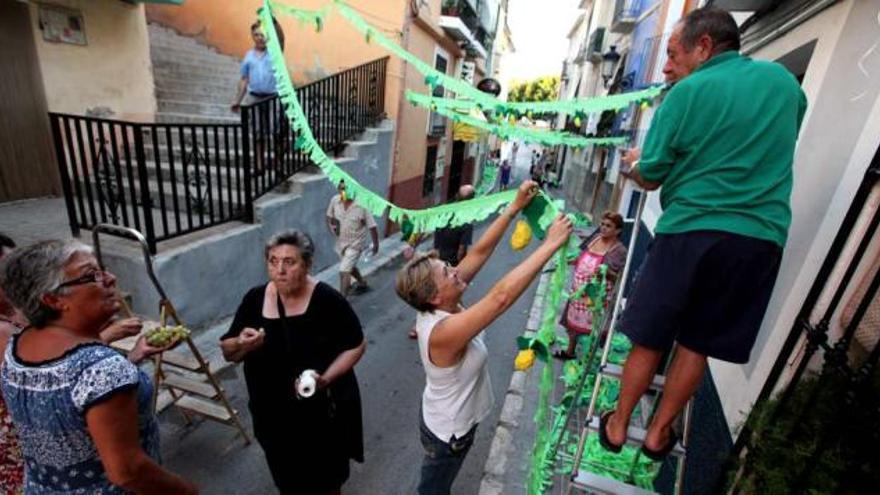 Varios vecinos colocan las guirnaldas hechos por ellos mismos para decorar la calle.