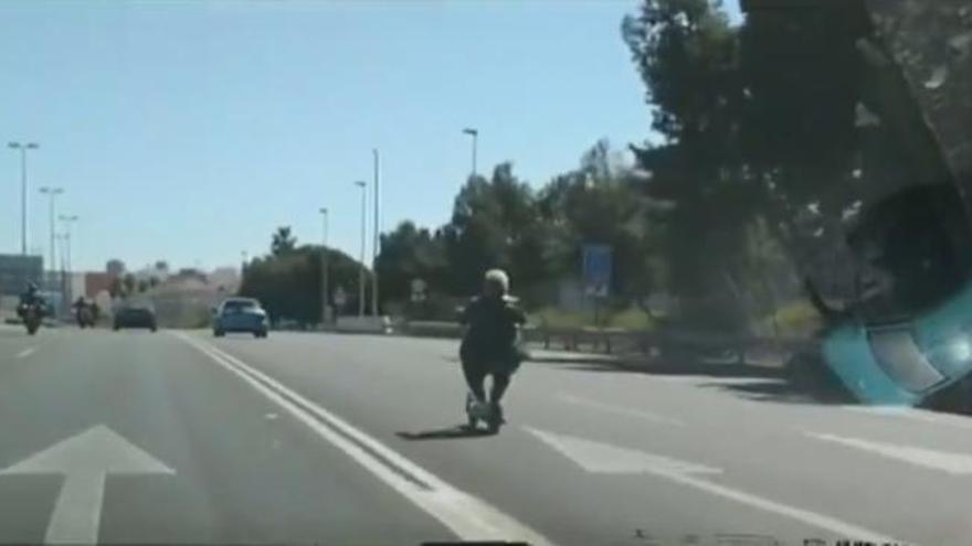 Una mujer circula en patinete y con auriculares por una autovía de cinco carriles