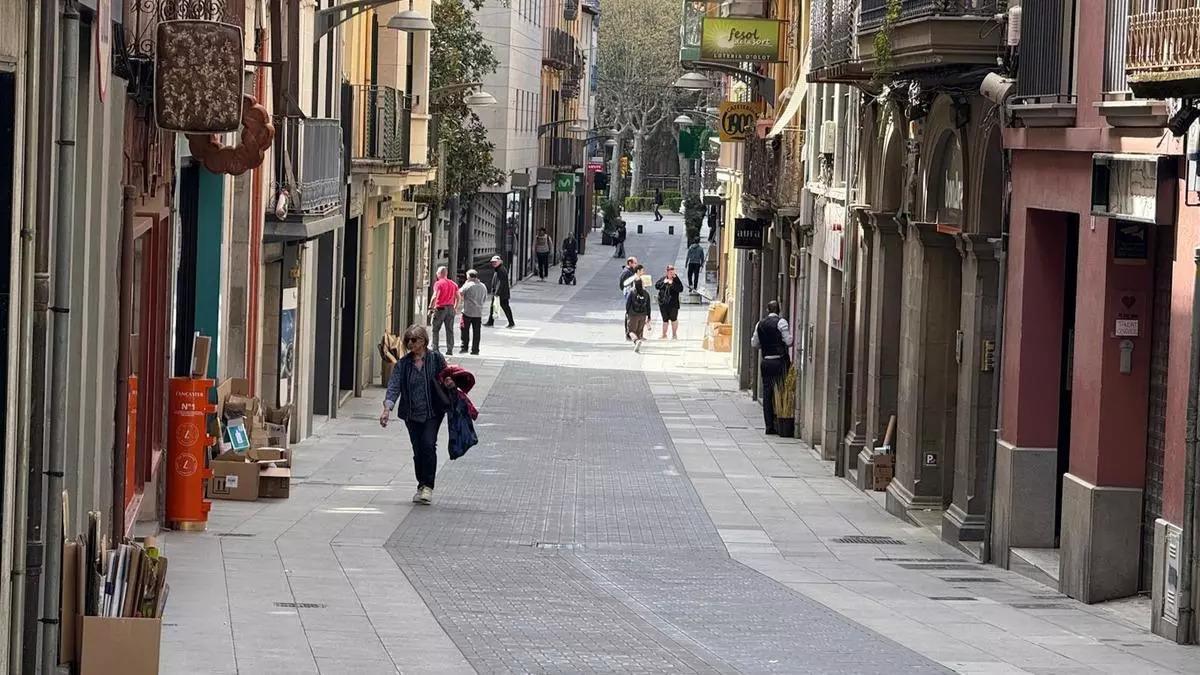 Diverses persones passegen per un carrer del nucli antic d'Olot.