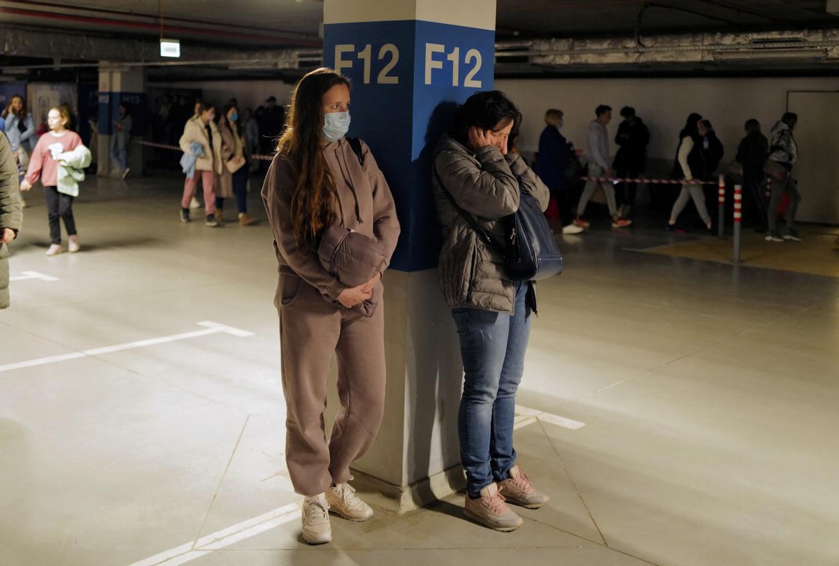 Una mujer reacciona mientras se refugia en el estacionamiento del centro comercial, mientras se escuchan sirenas de ataque aéreo, en medio de la continua invasión de Rusia a Ucrania.