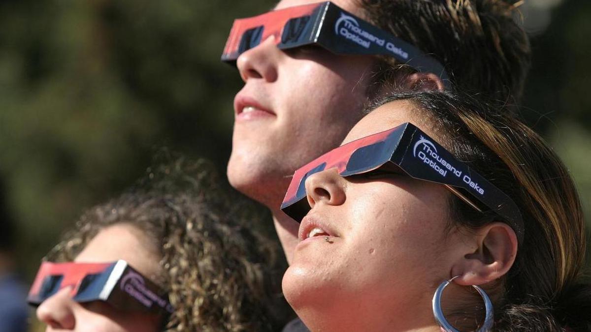 Tres noies fent ús de les ulleres especials per veure l’eclipsi, en una imatge d’arxiu.