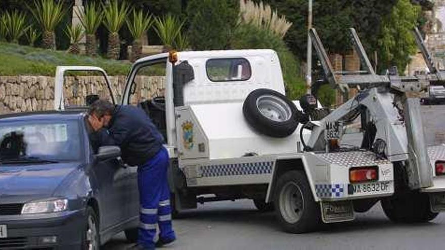 Un operario del servicio municipal de grúas retira un vehículo en el Centro.